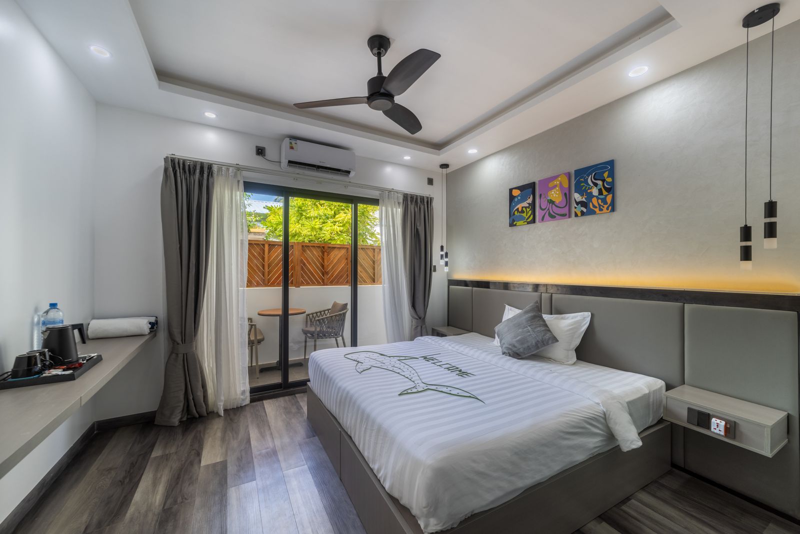 Deluxe Double Room at Kirulhiya Maldives with bed, desk and ceiling fan