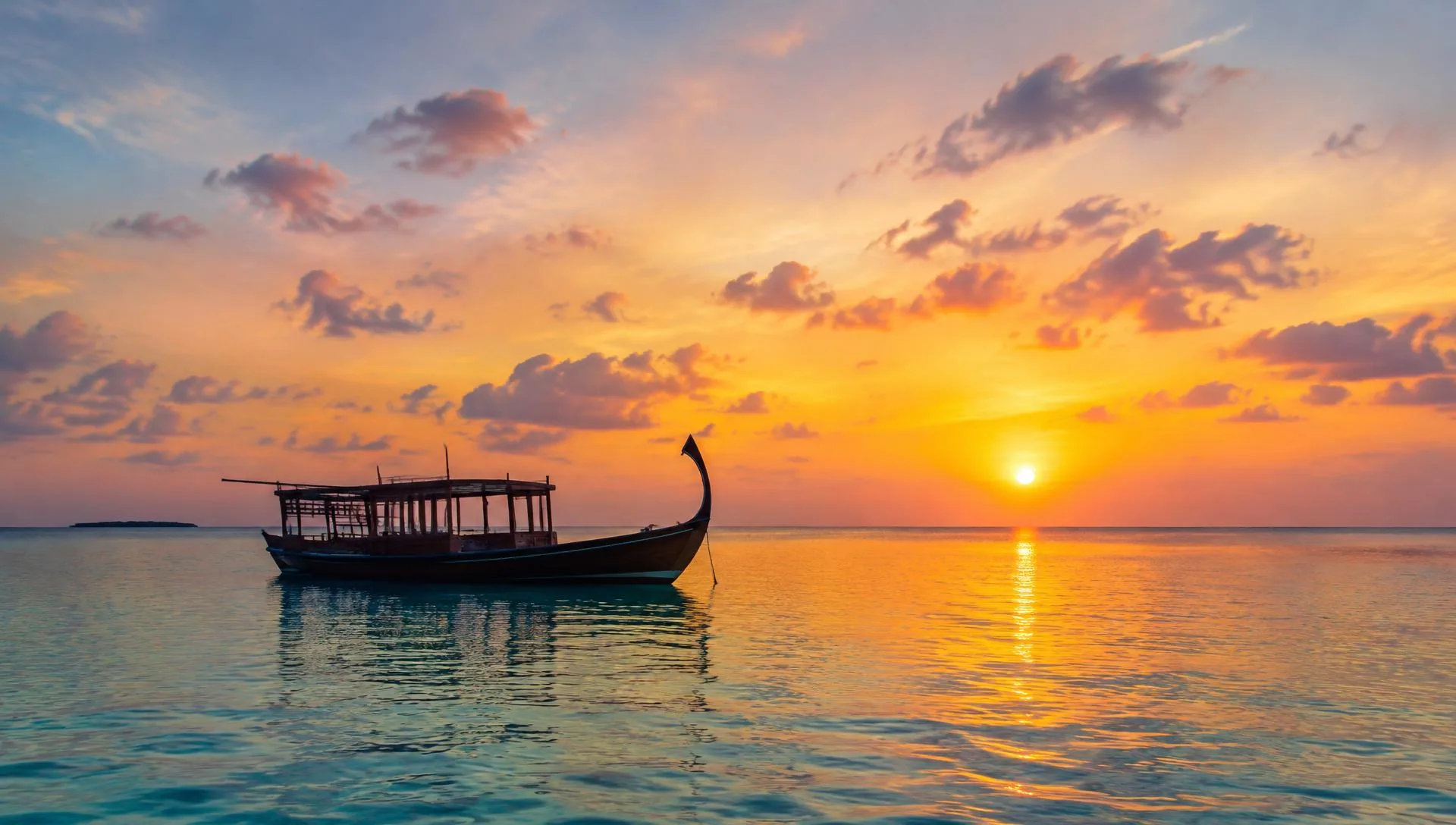 A traditional Maldivian dhoni boat on calm water at sunset